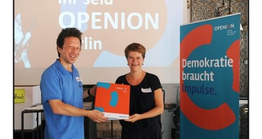 Meike Reinecke von der DKJS übergibt einen Ordner zum Start der Projektverbünde in Berlin