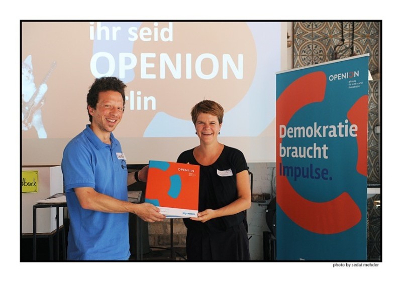 Meike Reinecke von der DKJS übergibt einen Ordner zum Start der Projektverbünde in Berlin